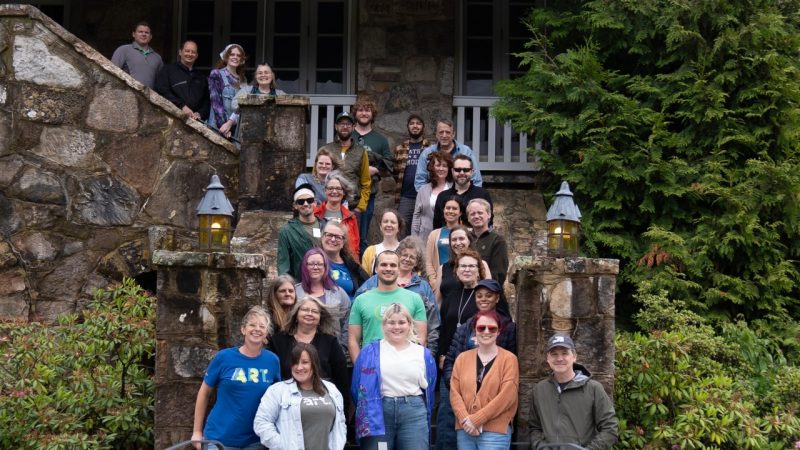  The staff of the Moss Arts Center stands on an outdoor stone staircase during a staff retreat.