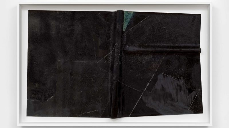 Charisse Pearlina Weston's "are there other pits deeper down?," 2024, a canvas etched with glass, frit, oil stick, silicone carbide, and epoxy. The canvas looks like a stiff sheet of fabric covered in black texture.