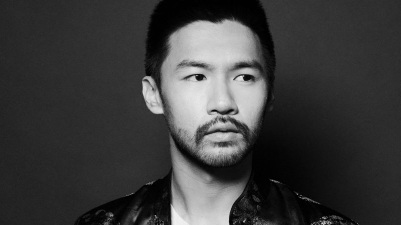  Conrad Tao, an Asian man with dark hair and a closely trimmed beard, looks off to the right of the frame in this black and white image