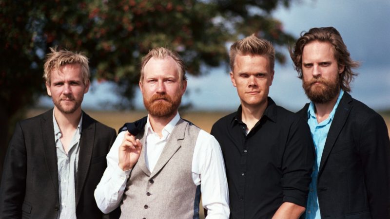  Members of the Danish String Quartet stand in a field with a tree behind them, wearing button down shirts and jackets