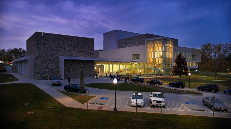  The front of the Moss Arts Center at night. Image shows the ADA parking spaces in front of the building.