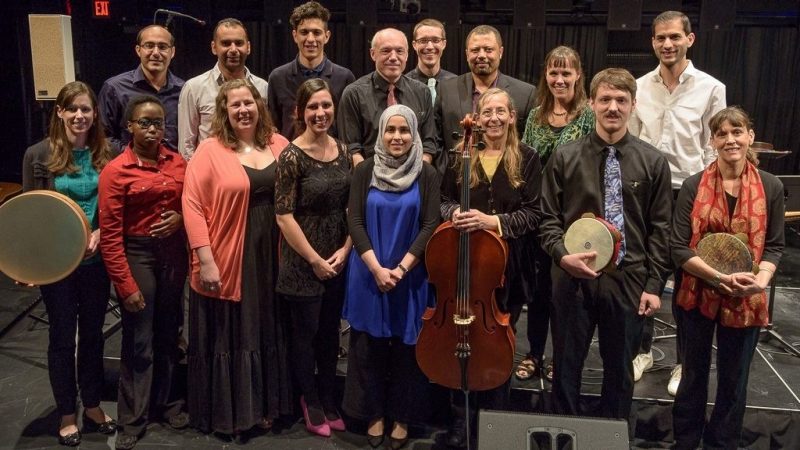  Members of the Itraab Arabic Music Ensemble stand for a group photo backstage at the Moss Arts Center, some holding their instruments