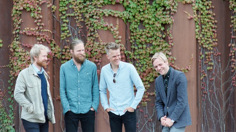  The members of the Danish String Quartet, four white men with reddish-blonde hair in long sleeve button downs, strand in front of an ivy-covered wall