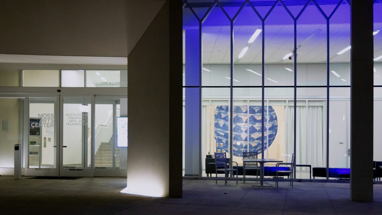  Namwon Choi's "The Shape of Distance" as seen at night from the front patio of the Moss Arts Center. A large blue circular mural covers the back wall of the gallery.