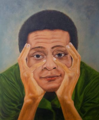  An oil self-portrait by Rodney Kimbangu, a caramel-colored Black man with a short afro and a green shirt. He wears an easy smile and cradles his face between both hands.