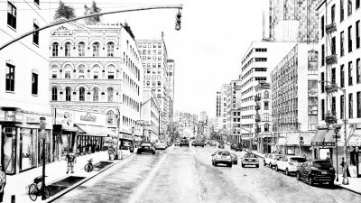  A black and white graphite drawing by Maclean Toman of a city street. A single stoplight arches over the road, and multilevel buildings line the street. Cars are parked along the sides of the street and traffic moves through the area.