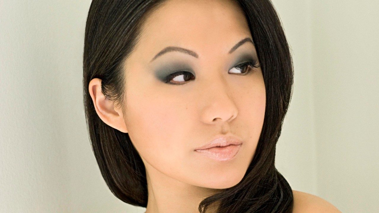  Violinist Sarah Chang, an Asian woman with long dark brown hair, smoky eye makeup, and nude lipstick.