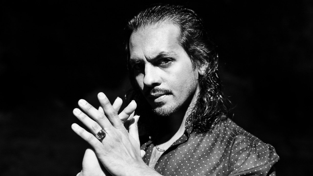   Flamenco dancer Farruquito wears a black and white polka dot shirt and claps his hands together in this black and white image.