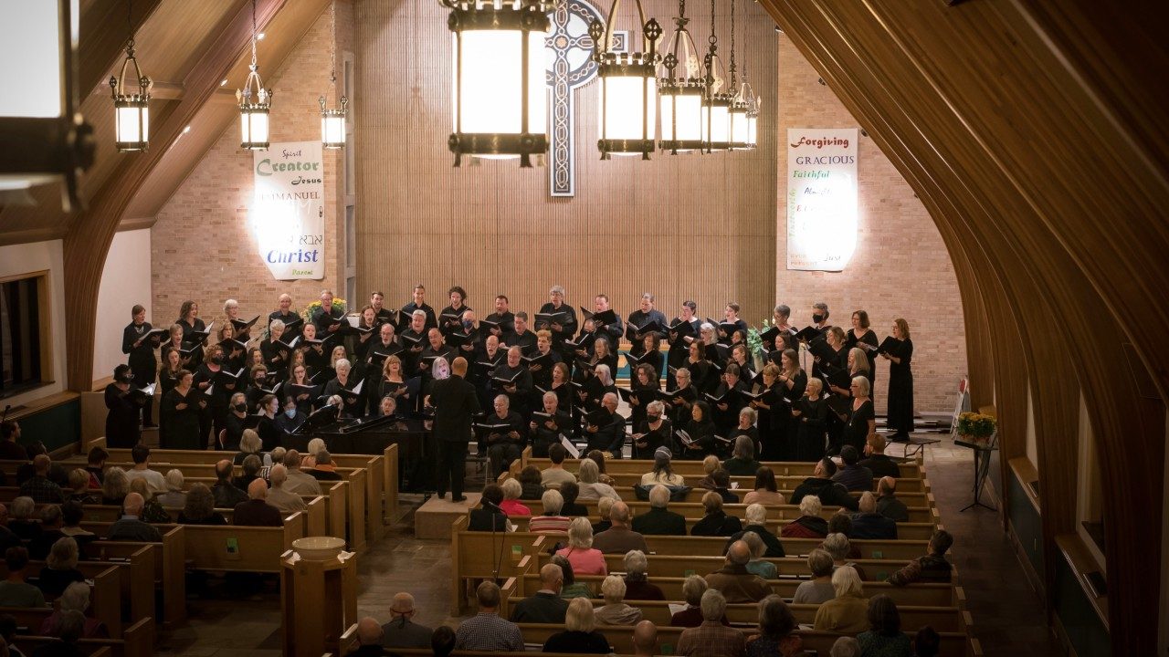  Blacksburg Master Chorale performs in a church, sweeping wooden arches trailing up the walls to the ceiling.