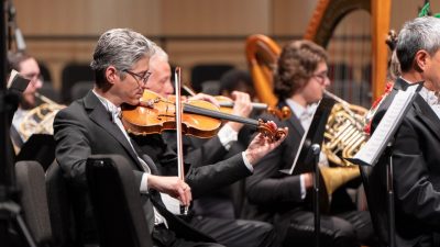  The Roanoke Symphony Orchestra performs its annual "Holiday Pops Spectacular" at the Moss Arts Center. In the foreground, an older man with salt and pepper hair plays the violin.