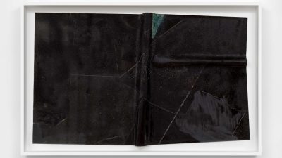 Charisse Pearlina Weston's "are there other pits deeper down?," 2024, a canvas etched with glass, frit, oil stick, silicone carbide, and epoxy. The canvas looks like a stiff sheet of fabric covered in black texture.