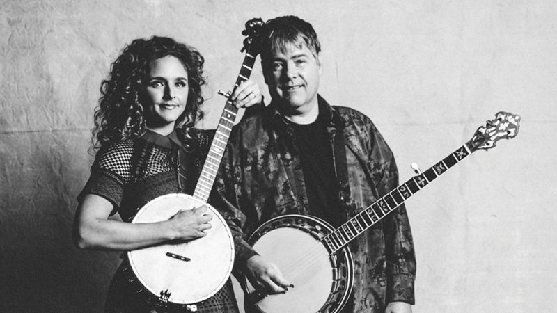 Banjoists Béla Fleck and Abigail Washburn  each hold a banjo and smile towards the camera in this black and white image.