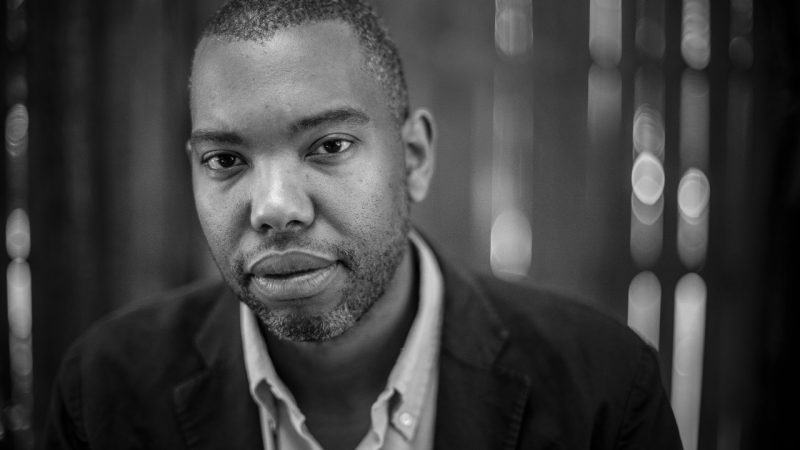 Author Ta-Nehisi Coates, a middle aged Black man with short hair and beard, wears a dark blazer over a light button down shirt in this black and white photo.