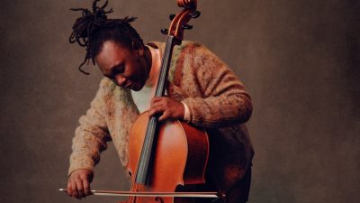 South African cellist Abel Selaocoe stands and plays his cello, his eyes closed as he feels the music.