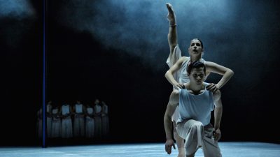 Members of Ballet BC wear white costumes as they perform on stage.