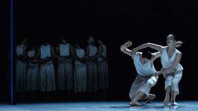 Members of Ballet BC wear white costumes as they perform on stage.