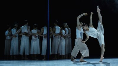Members of Ballet BC wear white costumes as they perform on stage.