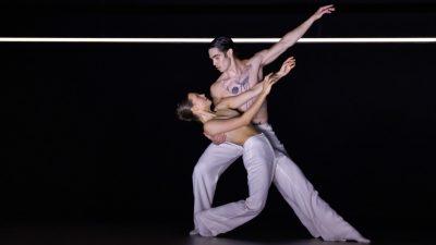 Members of Ballet BC wear white costumes as they perform on stage.