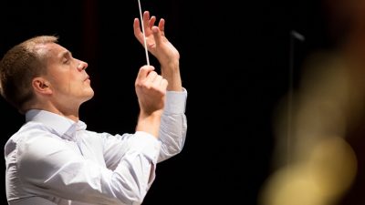 Music Director Vasily Petrenko leads the Royal Philharmonic Orchestra in a performance on stage.