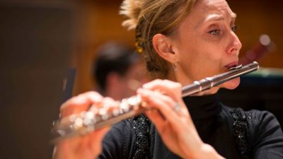 A member of the Royal Philharmonic Orchestra plays a flute during a concert.