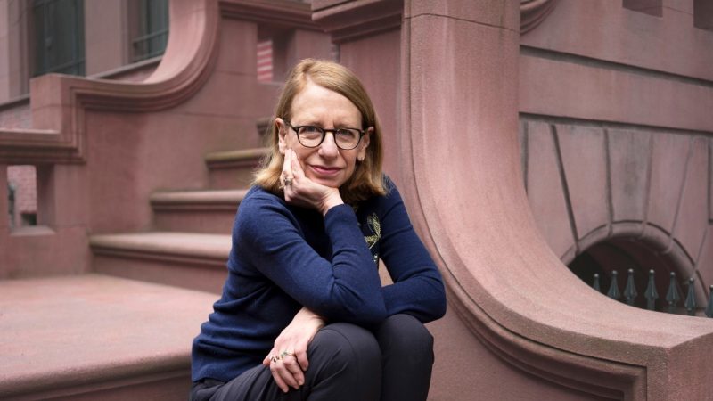 "New Yorker" cartoonist Roz Chast sits on the steps of a New York brownstone in a navy blue long-sleeved shirt.