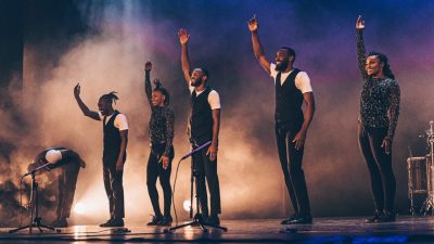 Members of Step Afrika! accept applause from the audience during a performance on stage.