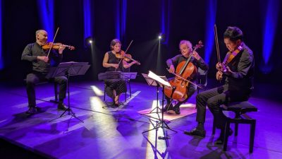 The Takács Quartet performs on stage in concert attire.