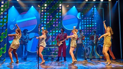 Cast members of "TINA – The Tina Turner Musical" perform on stage.