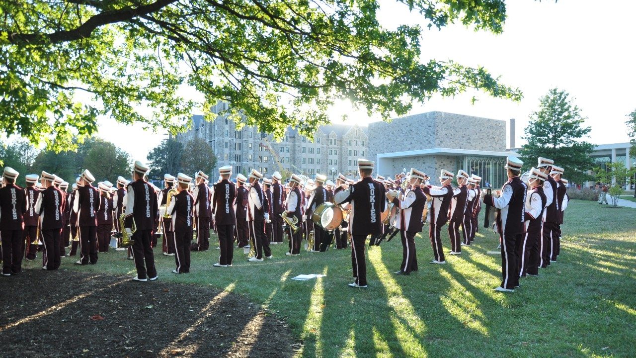  Marching Virginians perform on the Moss Arts Center's front lawn on a bright, sunny day.