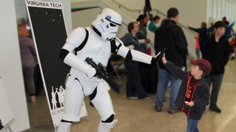  Storm Trooper character high-fiving a young boy in the grand lobby at Science Festival.