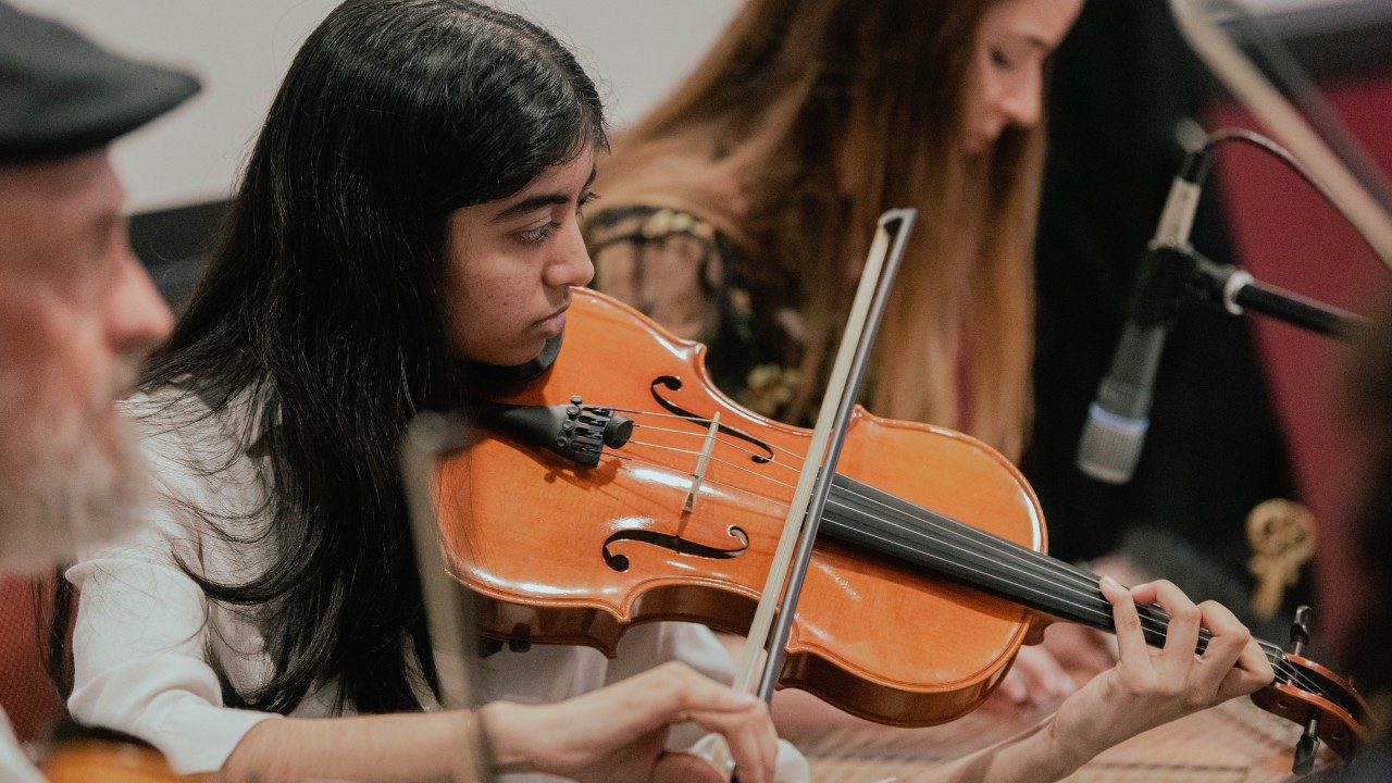 A young brown girl plays a violin