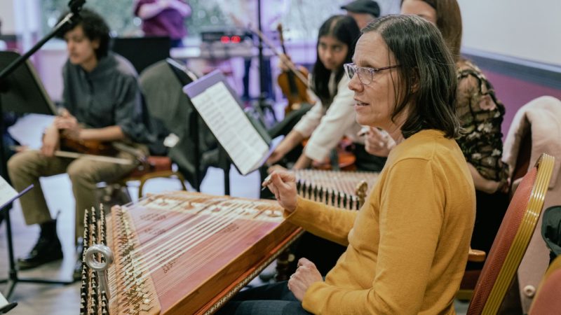 Itraab Music Ensemble Director Anne Elise Thomas sits at a qanun alongside other musicians.