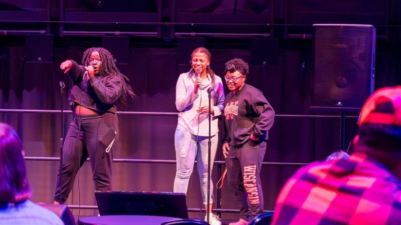 Virginia Tech students, three young Black women in casual clothes, belt it out during a free Broadway karaoke event in the Cube at the Moss Arts Center.