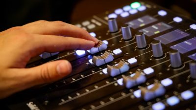 Virginia Tech student Kieran Casey's hand on a mixing board as he composes a new work in a studio.