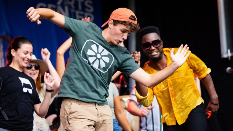 Virginia Tech students dance on stage with Cimafunk during a performance at the Moss Arts Center