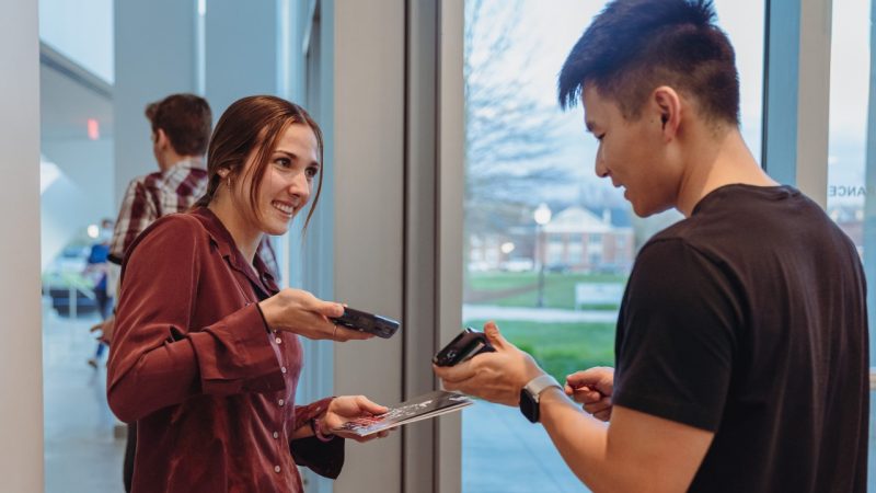  A young white female student employee scans the ticket of a young Asian man as he enters the performance hall at the Moss Arts Center.