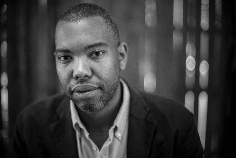 Author Ta-Nehisi Coates, a middle aged Black man with short hair and beard, wears a dark blazer over a light button down shirt in this black and white photo.